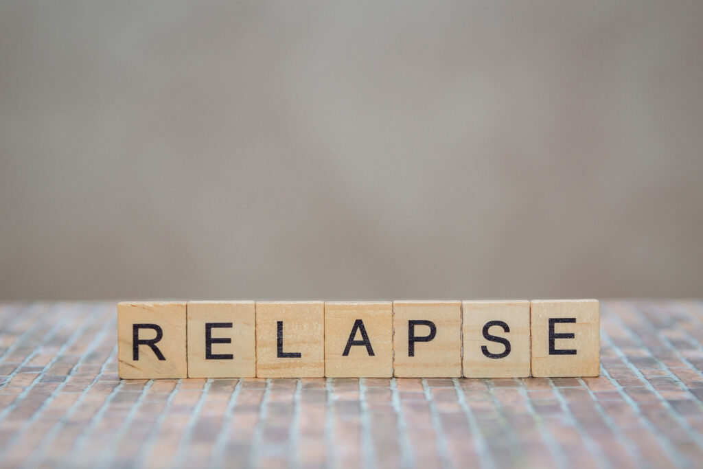 relapse spelled out with scrabble blocks while someone in the background discusses preventing relapse in co-occurring disorders