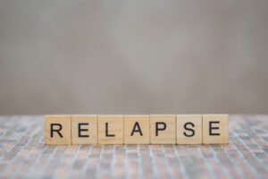 relapse spelled out with scrabble blocks while someone in the background discusses preventing relapse in co-occurring disorders