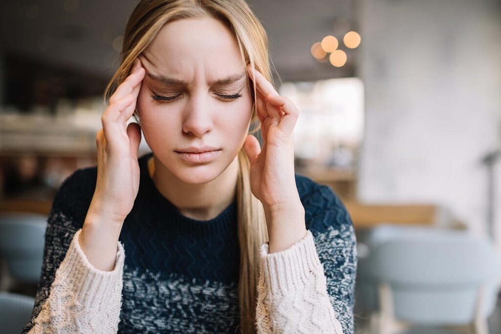 woman with hands on head experiencing opiate withdrawal symptoms