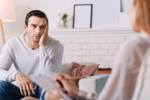 man with head in hands talks with a therapist about benzodiazepine withdrawal symptoms and treatment