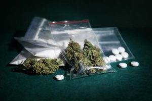 Pills and marijuana on table demonstrating the effects of synthetic marijuana