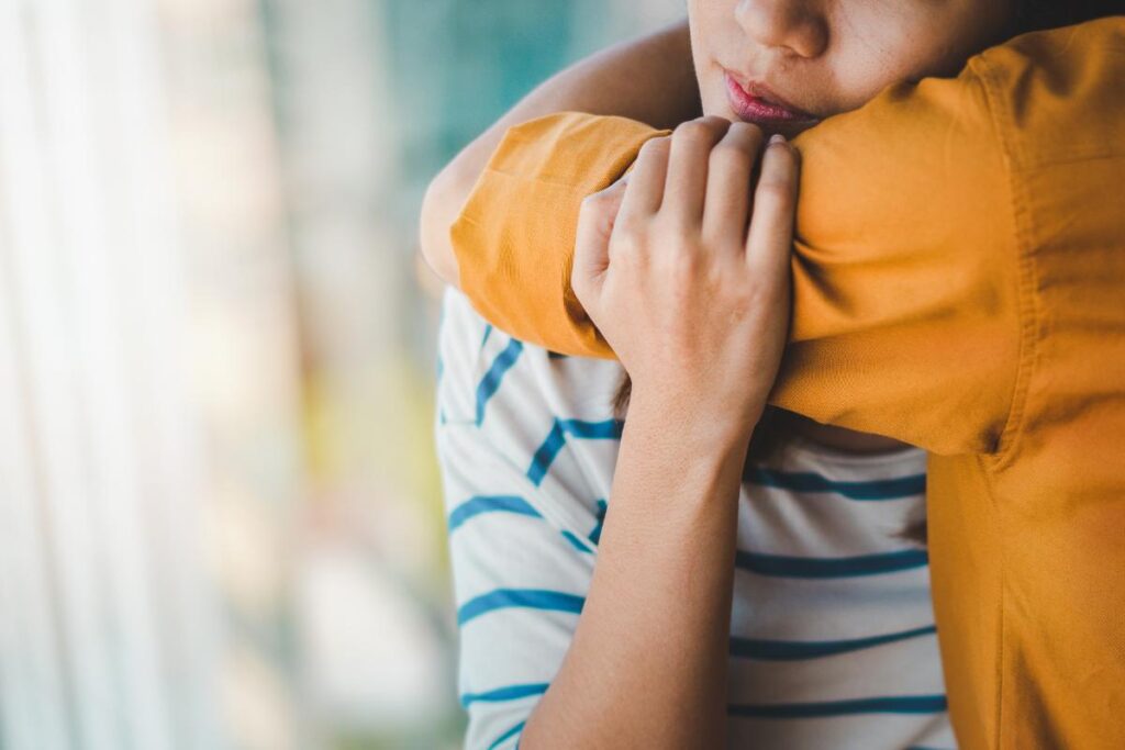 person in striped shirt hugging person in yellow shirt and learning about finding the right addiction therapy programs