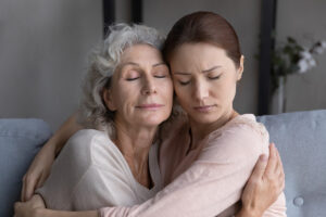 a mother and daughter hug while discussing the signs of moms who drink too much
