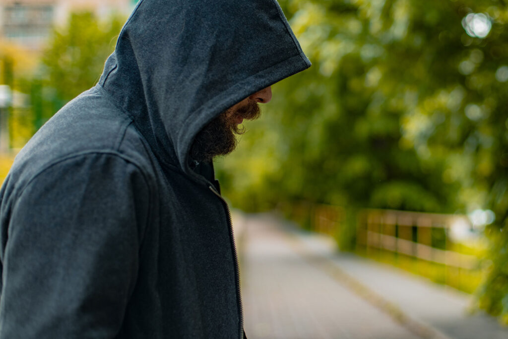 a man wearing a hoodie is outside and is thinking about the dangers of fentanyl use