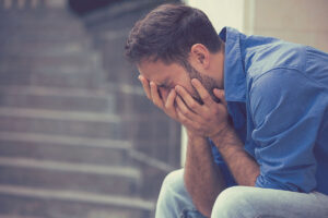 a man sits with his hands covering face struggling with benzo overdose symptoms