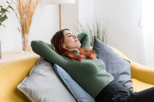 woman with red hair relaxes on her couch and thinks about how good it feels to have the motivation to stay sober