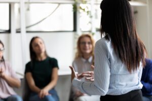 a woman speaks to a group and answers one of the group members question of can I work while in rehab