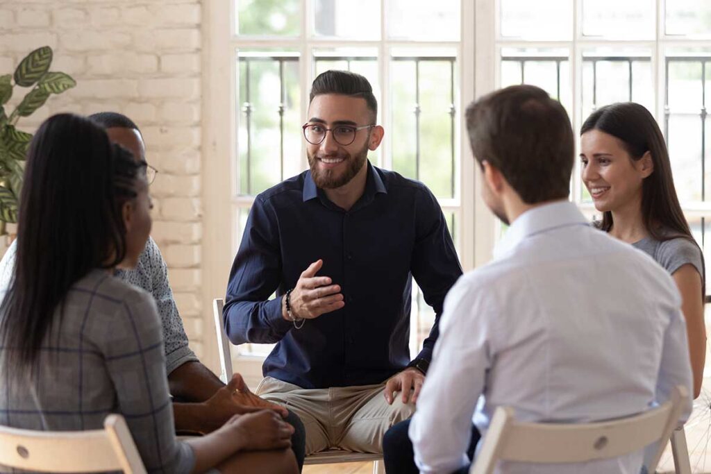 a man talks to a group of people about inpatient vs. outpatient rehab options for them