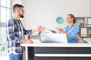 a medical professional hands a form about acpn health insurance coverage for addiction treatment to a male patient to fill out