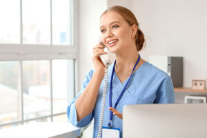 a medical professional holds a phone to her ear while talking to a patient about american behavioral insurance coverage for rehab