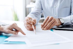 two people sit near each other going over and pointing at a document that explains what types of addiction treatment are covered by insurance