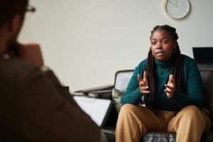 a person sits in a chair and is talking with their hands while talking to a therapist in their polysubstance abuse treatment