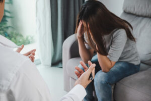 an upset woman holds her hands to her face while sitting and talking to her therapist about heroin detox