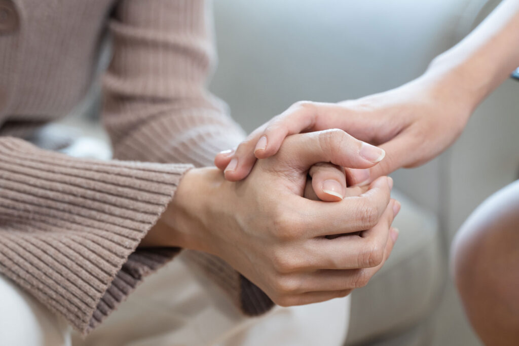 a person holds another person's hands that are clasped together while telling them the benefits of holistic therapy