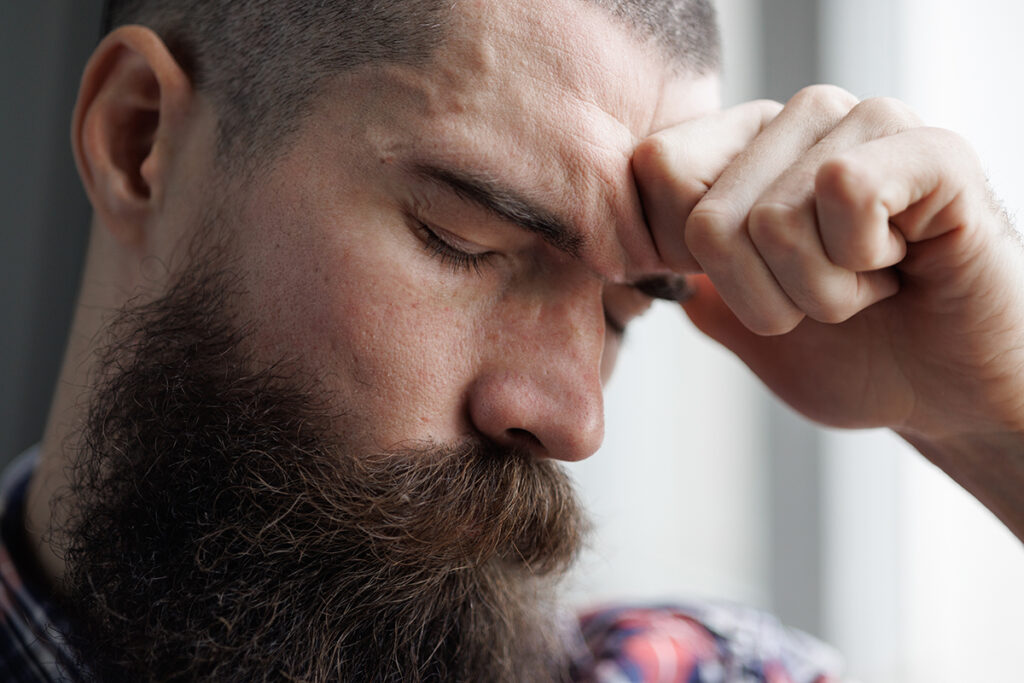 a man holds his head as he deals with adderall side effects
