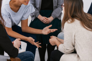 a group of people sit together in a circle while talking about how residential detox has helped them