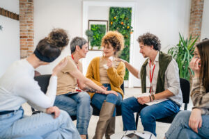 a group of people sit in a circle consoling one member after she asks about getting addiction help and what is intensive outpatient program