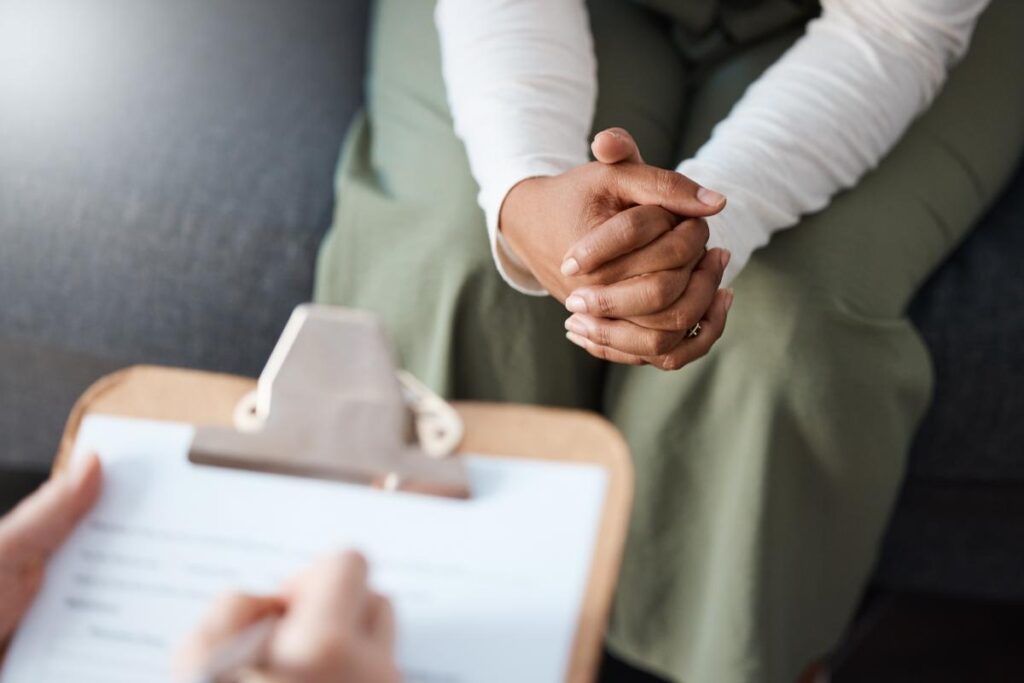 a person sits with hands in their lap with another person with a clipboard writing about what to expect after emdr