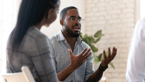 a man is talking with his hands to other group members in his 12 step program