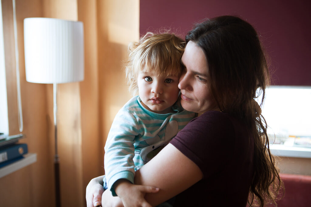 a mother holds her child as she thinks of the impact of alcoholism on family