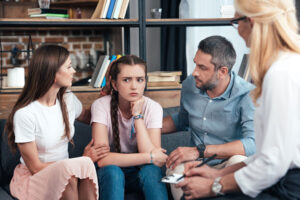 a family of three sit in family therapy talking about their experience with addiction