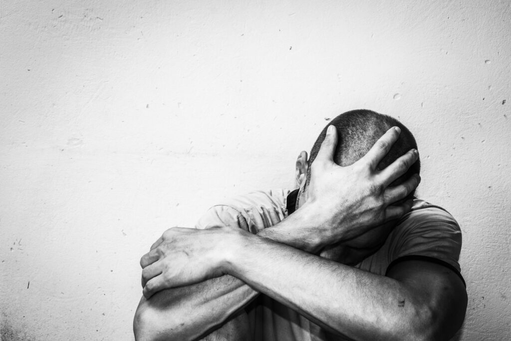 person holds their hand to the front of their face struggling with the stages of addiction