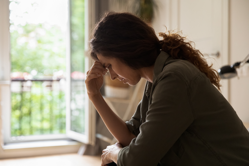 a struggling woman sits and holds her hand to her forehead trying to figure out her why she has a trauma response to a certain event