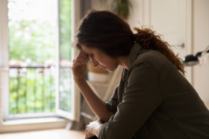 a struggling woman sits and holds her hand to her forehead trying to figure out her why she has a trauma response to a certain event
