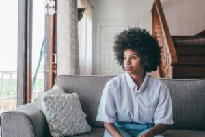 woman sits on a couch looking out the window wondering are edibles addictive