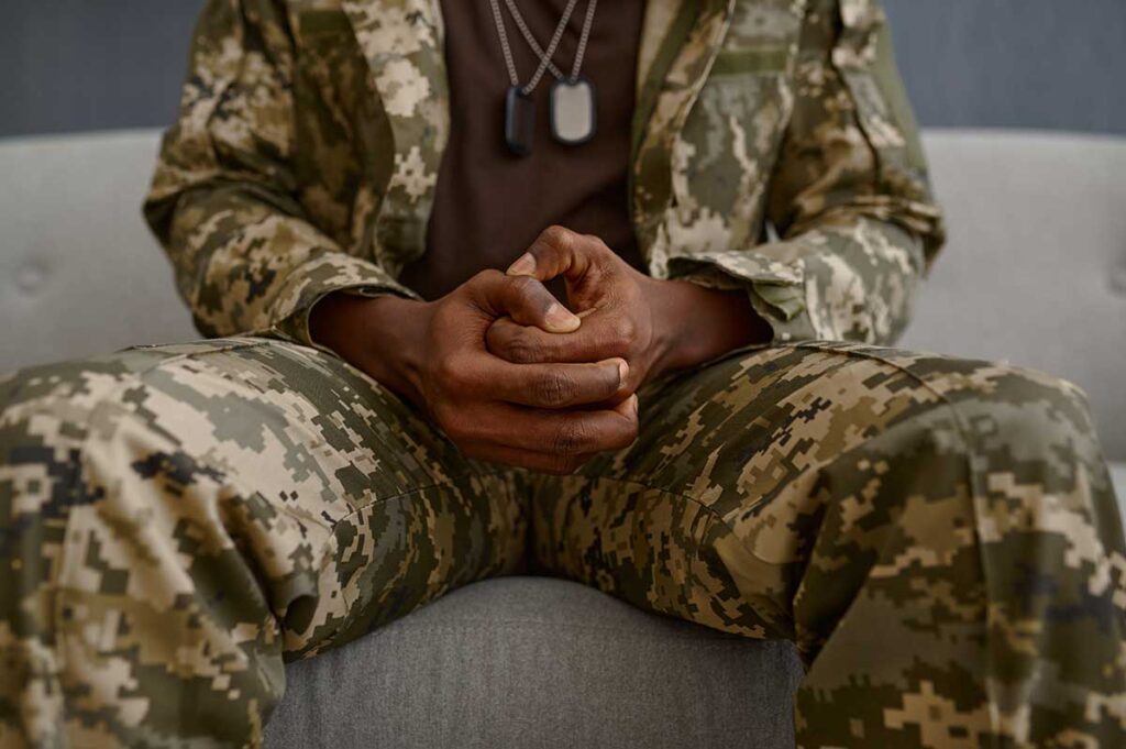 military person sitting on a couch with hands in lap while discussing the psychological effects of military service
