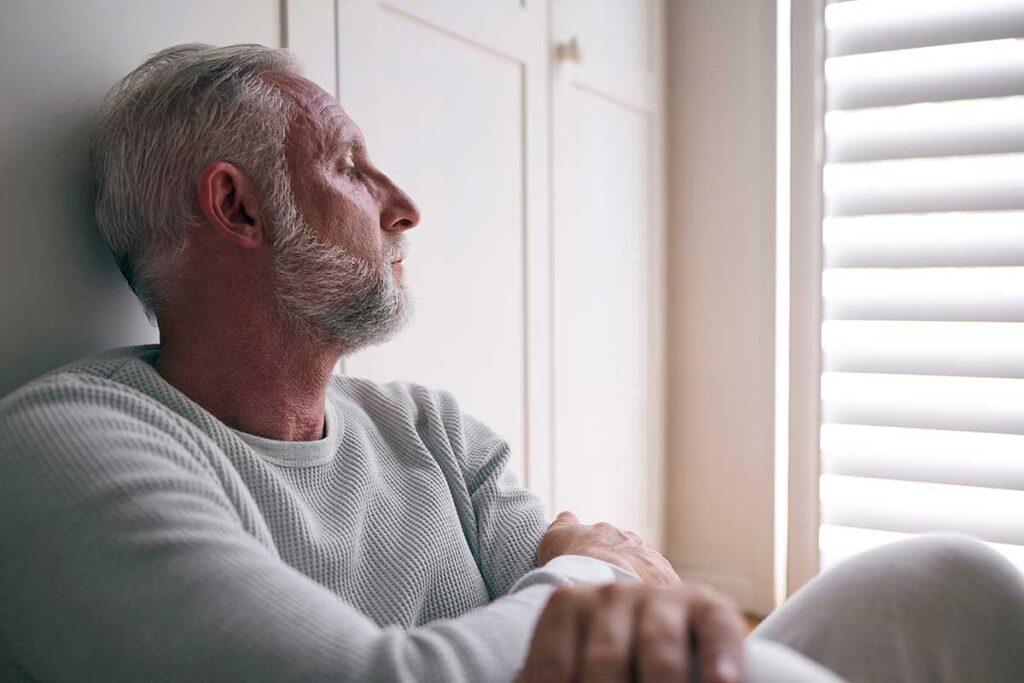 older adult man sits and looks out window thinking about the most addictive opioids