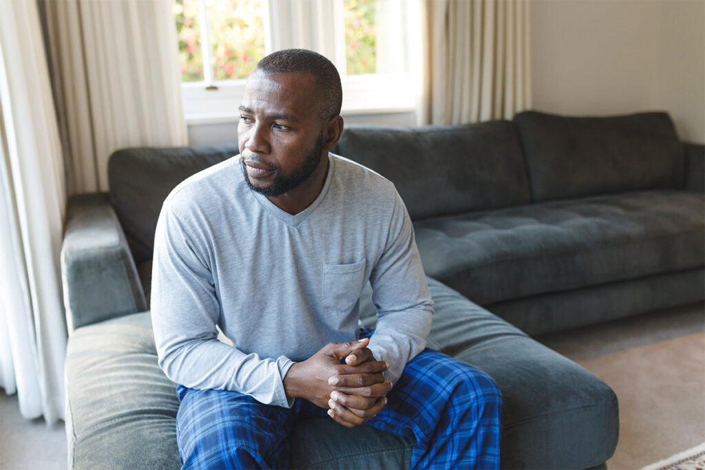 man sits on his couch looking out the window thinking about his drinking triggers