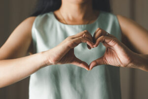 a person makes a heart with their hands to celebrate self-care in recovery